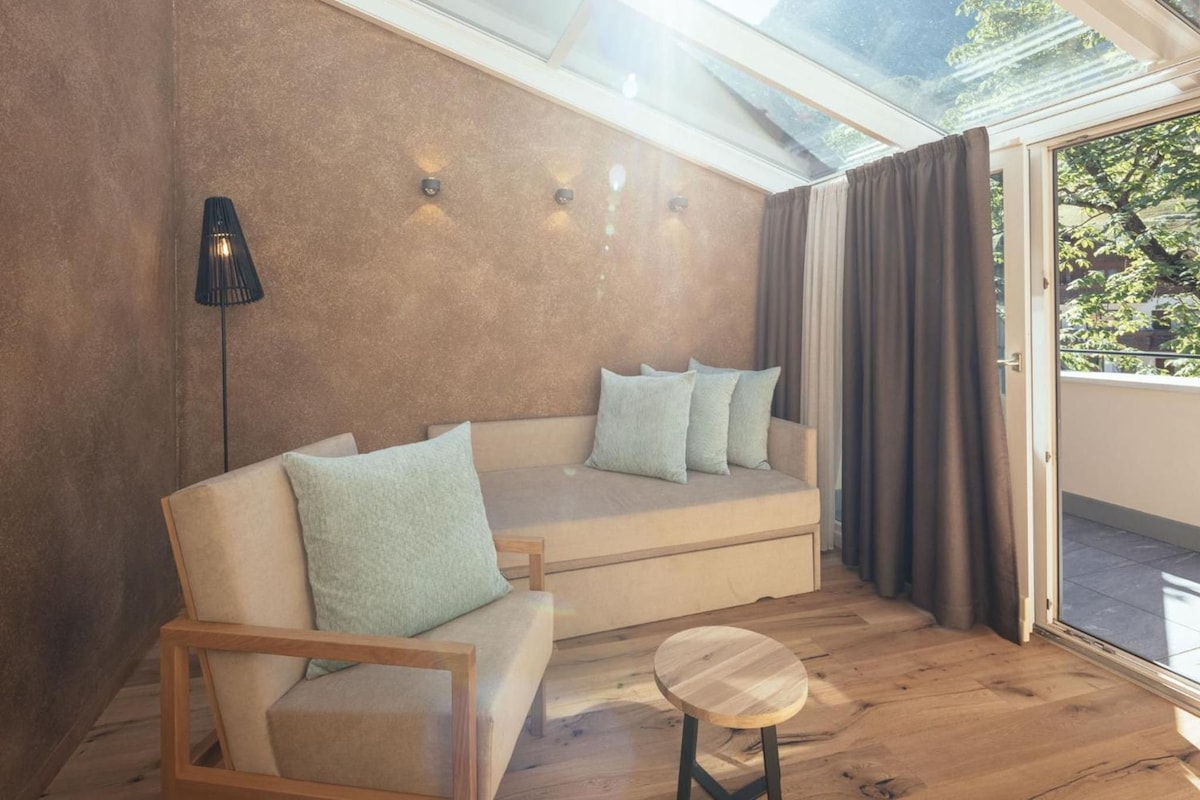 A modern living room with a sofa, a wooden chair, a small table, and a floor lamp.