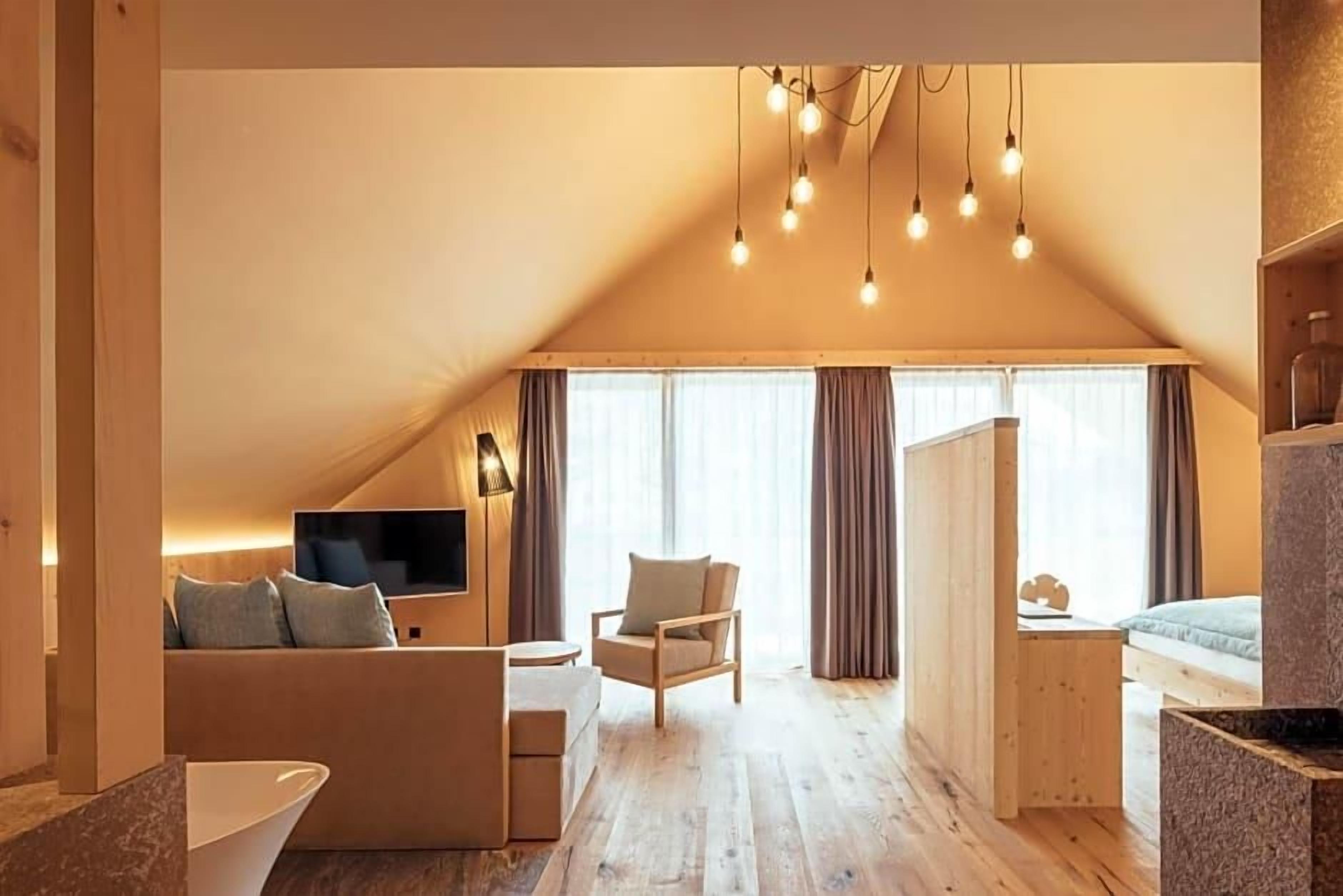 A cozy loft-style room with a sloped ceiling, a sofa, a chair, a small table, and a television.
