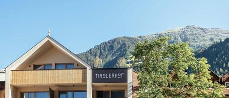 A hotel with a sign reading 'TIROLERHOF' in front of a mountain backdrop.
