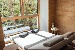 A bedroom with a large window, a bed with pillows, a small table with glasses, and a bottle. - Tiroler Hof (San Leonardo in Passiria)