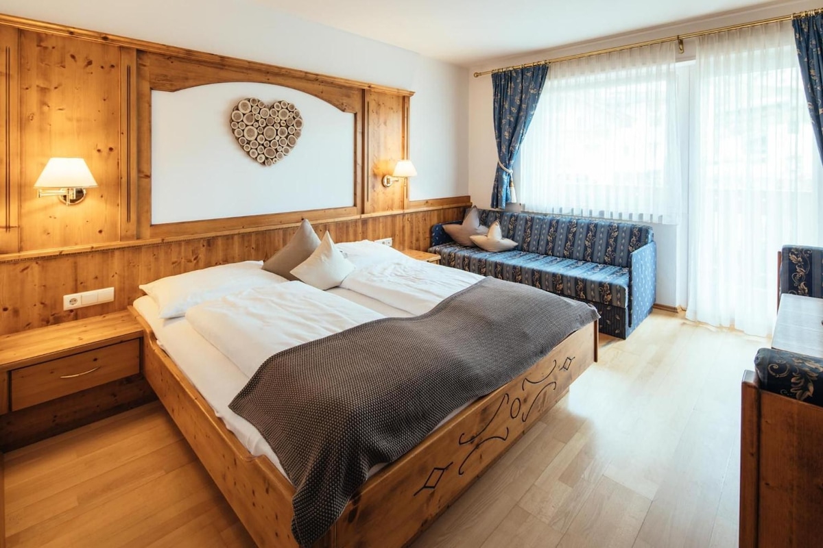 A wooden bedroom with a bed, bedside tables, a bench, and a wall-mounted heart decoration.