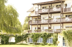 Um hotel com vários andares, varandas, janelas amplas e um jardim.