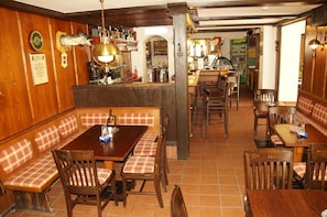 Interior de restaurante com cabines de madeira, mesas e um balcão.