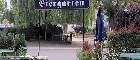 An outdoor seating area with a sign for 'Vieregatten' restaurant, surrounded by greenery and a stone pathway.
