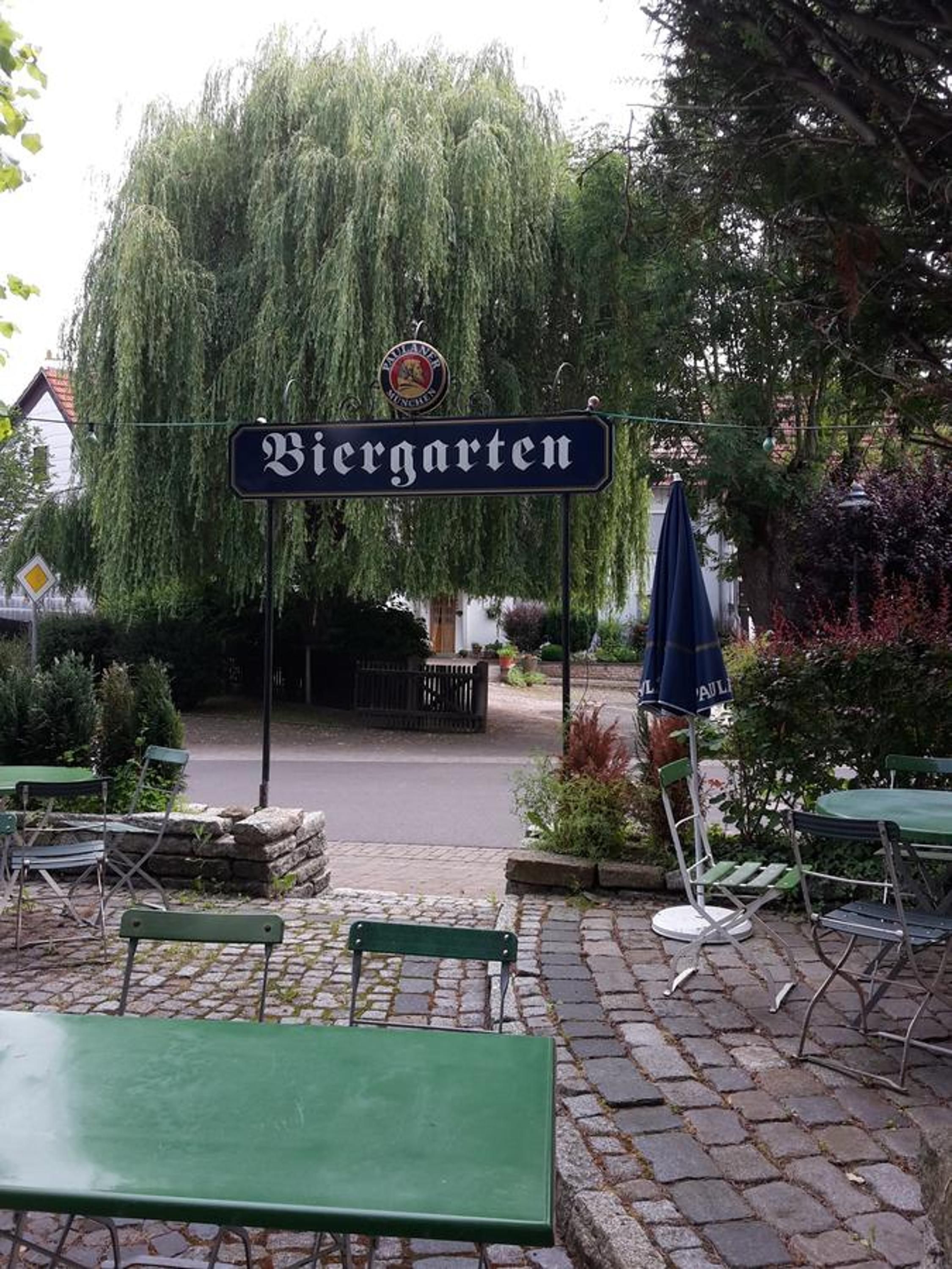An outdoor seating area with a sign reading 'Biergarten' and a beer garden sign above it.