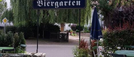 Un área de estar al aire libre con un letrero que dice 'Biergarten' y un cartel de jardín de cerveza arriba.