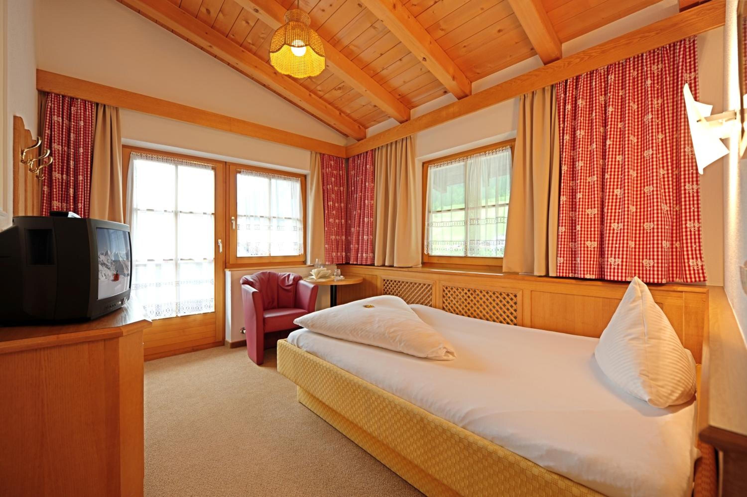Een hotelkamer met een bed, een televisie, een stoel en een tafel.
