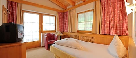 A hotel room with a bed, a television, a chair, and a table.