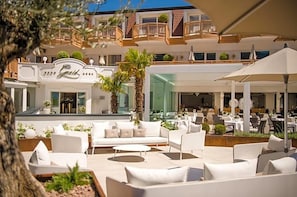 A hotel lobby with outdoor seating, a reception area, and a visible restaurant. - Gnaid (Tirolo)