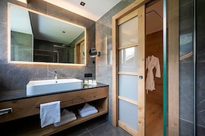 A modern bathroom with a large mirror, a sink, and a wooden vanity. - Gnaid (Tirolo)