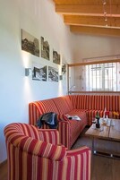 Sala de estar com sofá listrado, mesinha de centro e janela com grades.