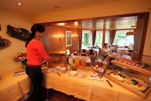 A buffet setup with various food items and a person serving.