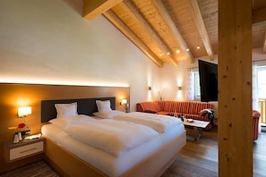 A hotel room with a large bed, a sofa, and a wooden ceiling. - Bellevue (Mittelberg)