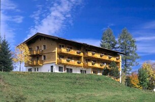Um edifício de vários andares com varandas, localizado numa encosta gramada.