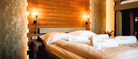A hotel room with a wooden headboard, a bed with white linens, and two wall-mounted lamps.