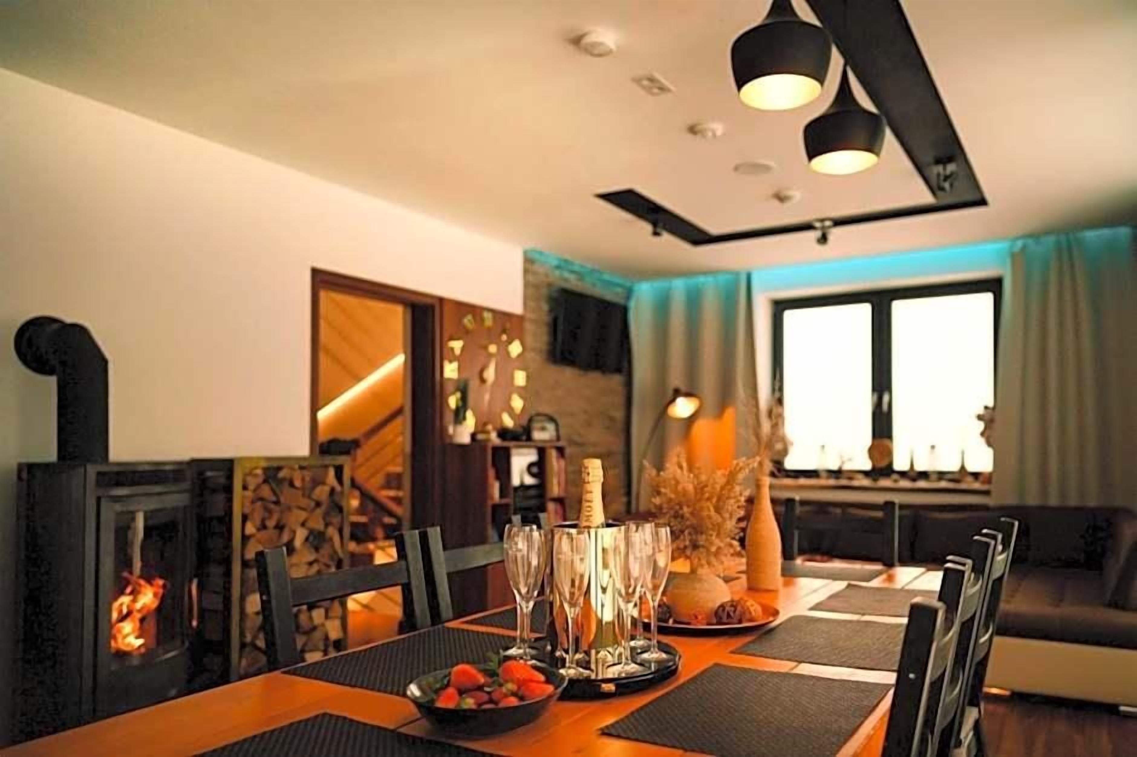 A dining area with a fireplace, a table set for a meal, and a sofa in the background.