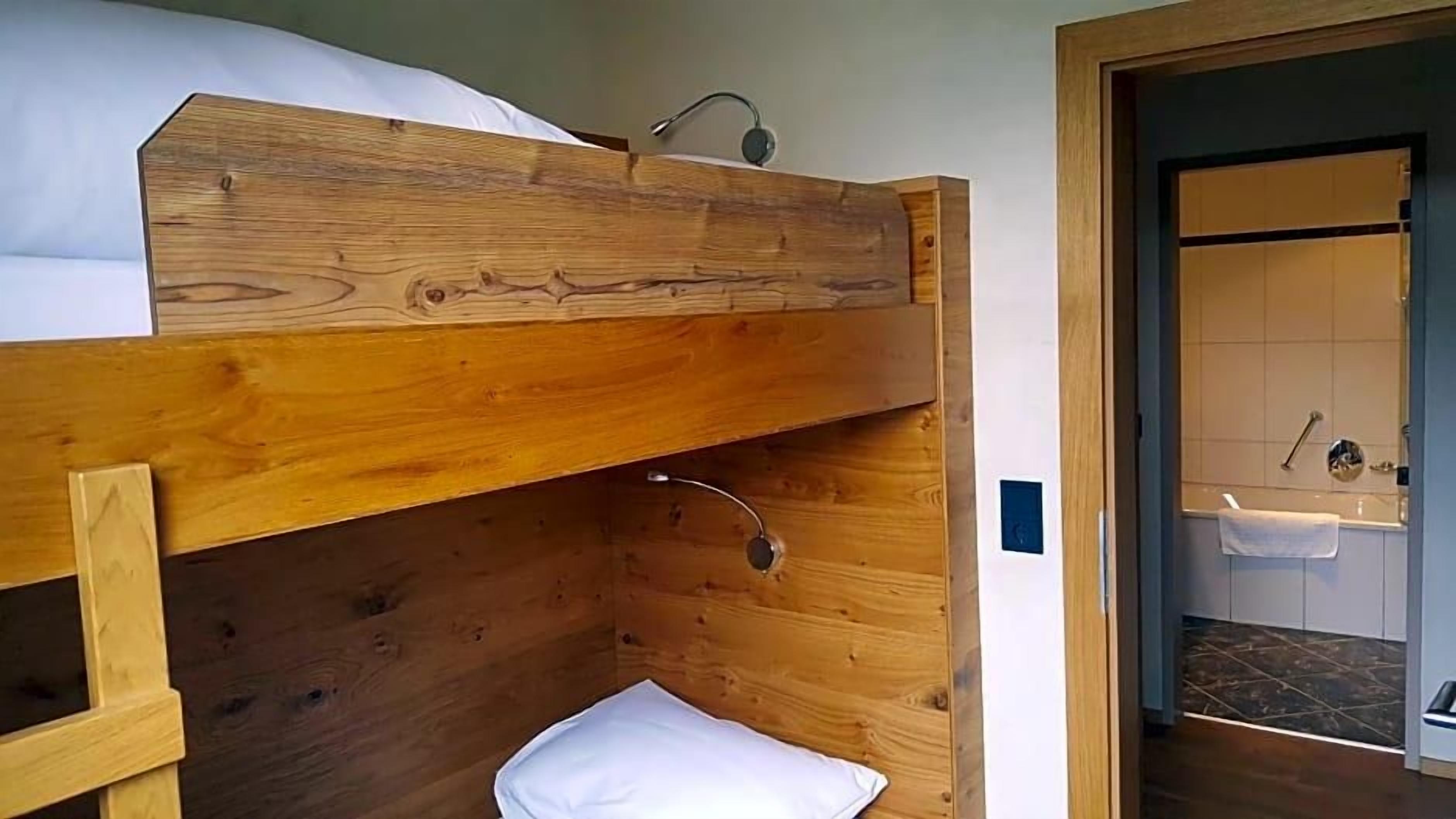 Ein Stockbett mit Holzkopfteil, einem kleinen Nachttisch und einem weißen Kissen.