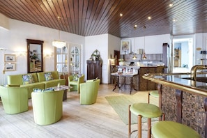 A modern living room with green sofas, a coffee table, and a kitchen area with a bar. - Kastanienhof (Bad Muender am Deister)