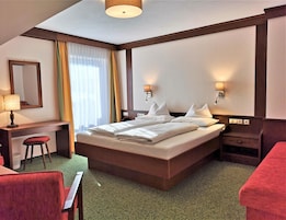 Habitación de hotel con una cama grande, un escritorio con una silla, un espejo y dos lámparas de noche.