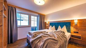 A bedroom with a bed, a window, wooden walls, and a ceiling light.