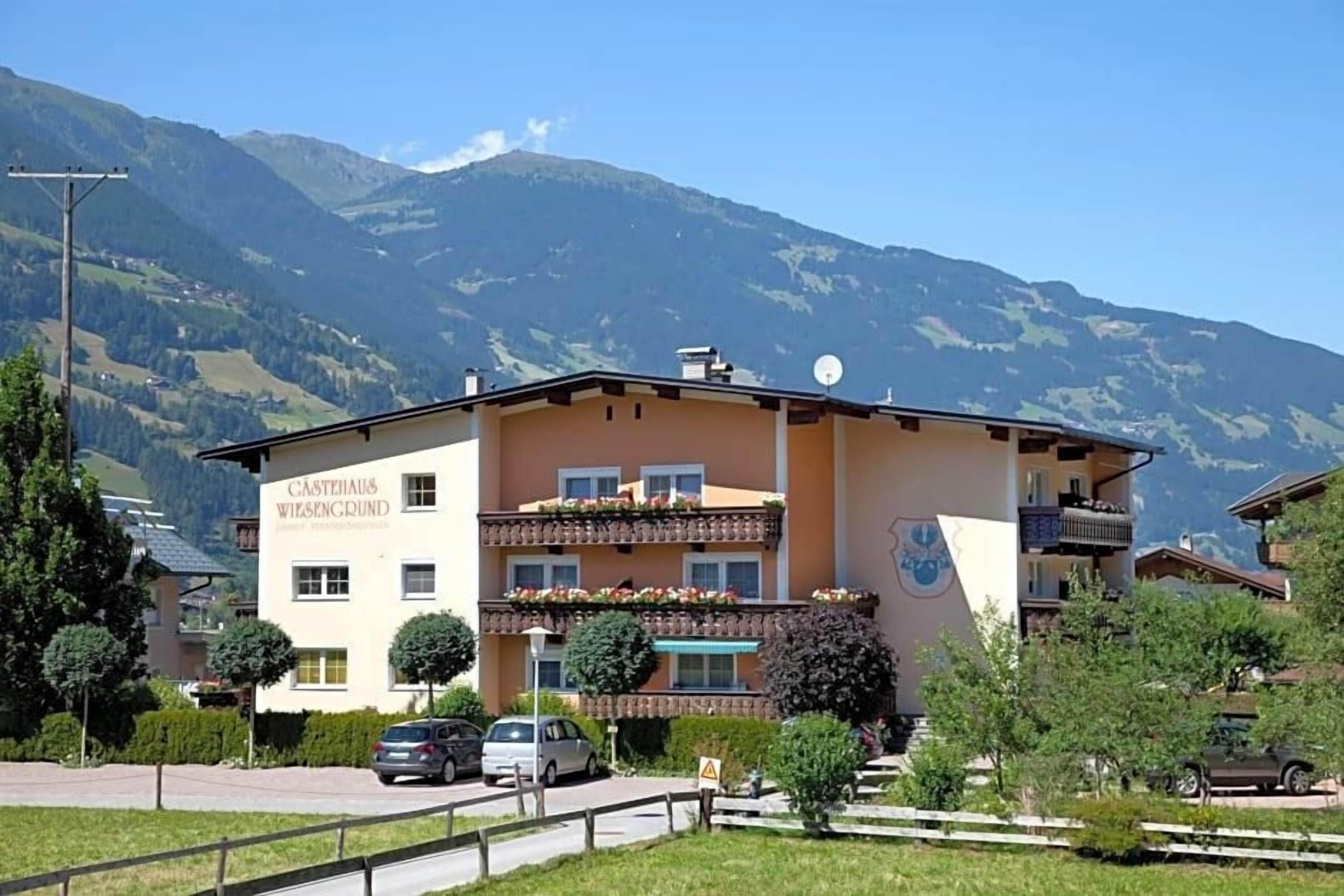 Un hotel con balcón, rodeado de vegetación y montañas.