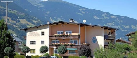 Un hotel con balcón, rodeado de vegetación y montañas.