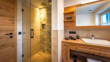 A modern bathroom with a glass-enclosed shower, wooden cabinetry, and a large mirror above the sink.