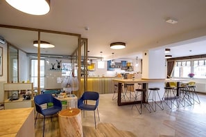 A modern kitchen with a central island, bar stools, and a dining area with blue chairs.