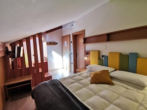 A hotel room with a bed, a desk, a chair, and a television.
