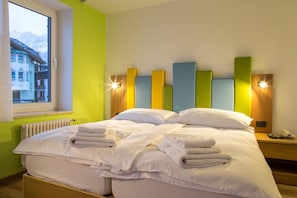 A hotel room with a bed, pillows, and a window with a view of buildings.