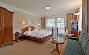 A hotel room with a bed, a sofa, a television, and a desk. - Waldheim (Mayrhofen)