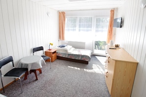 Un dormitorio con cama, escritorio, silla y televisor.