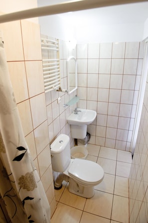 Un baño pequeño con inodoro, lavamanos y cortina de ducha.