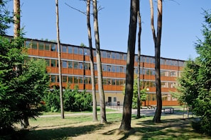 Un edificio moderno de varios pisos, rodeado de árboles y una zona verde.