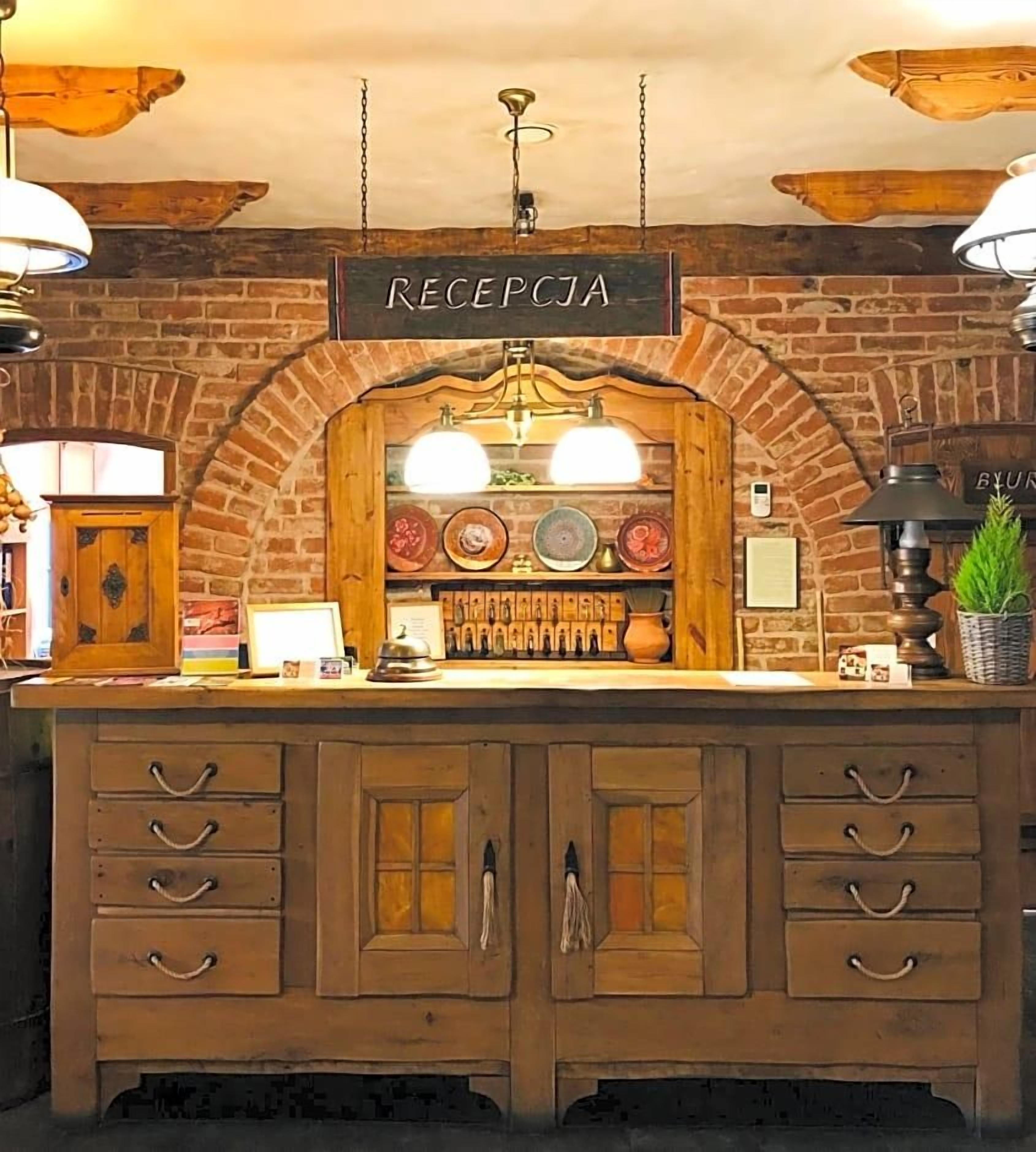 A reception area with a brick wall, wooden counter, and a sign labeled 'RECEPTICA'.