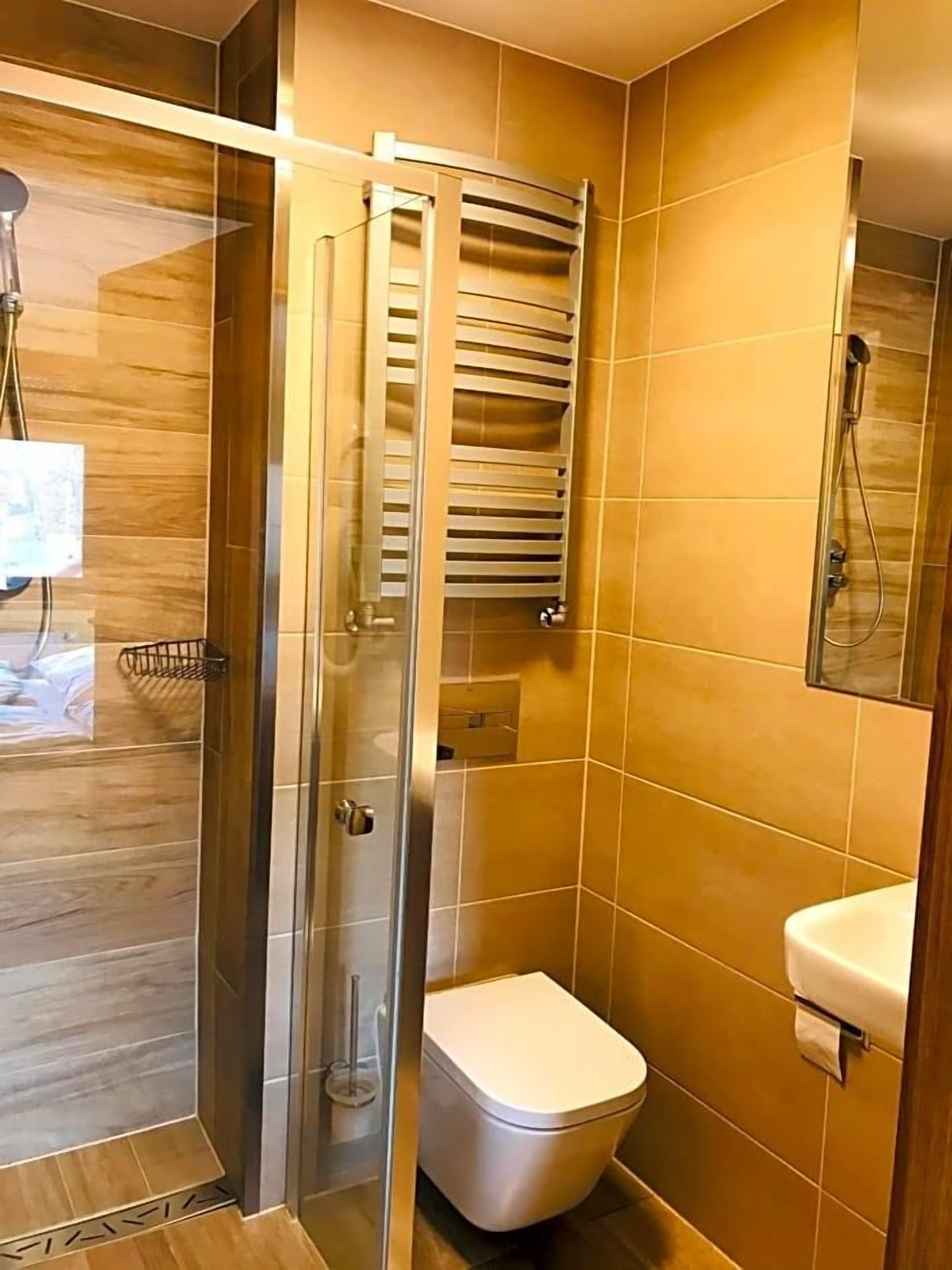 Un baño con cabina de ducha de vidrio, inodoro y lavamanos.