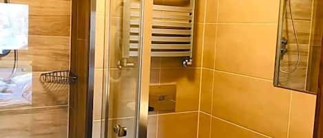Un baño con cabina de ducha de vidrio, inodoro y lavamanos.