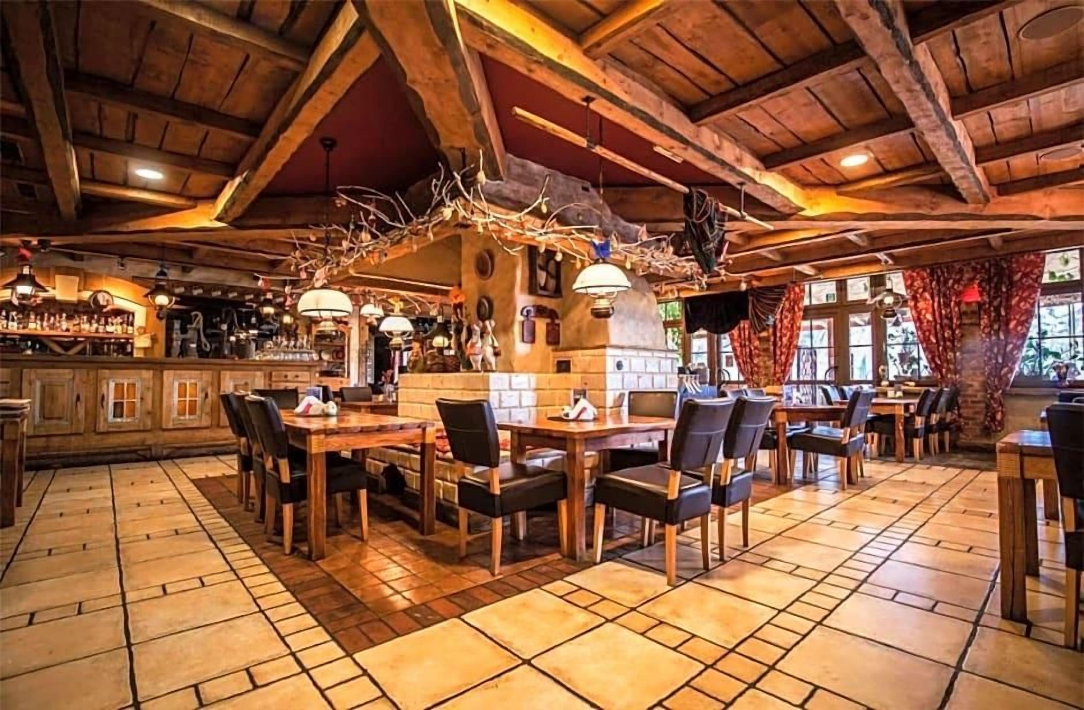 A rustic interior with wooden beams, stone flooring, and a bar area.