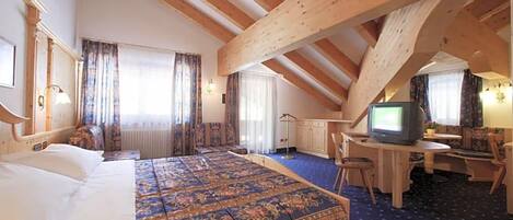 Une chambre d’hôtel avec un grand lit, une télévision, un bureau et une chaise.