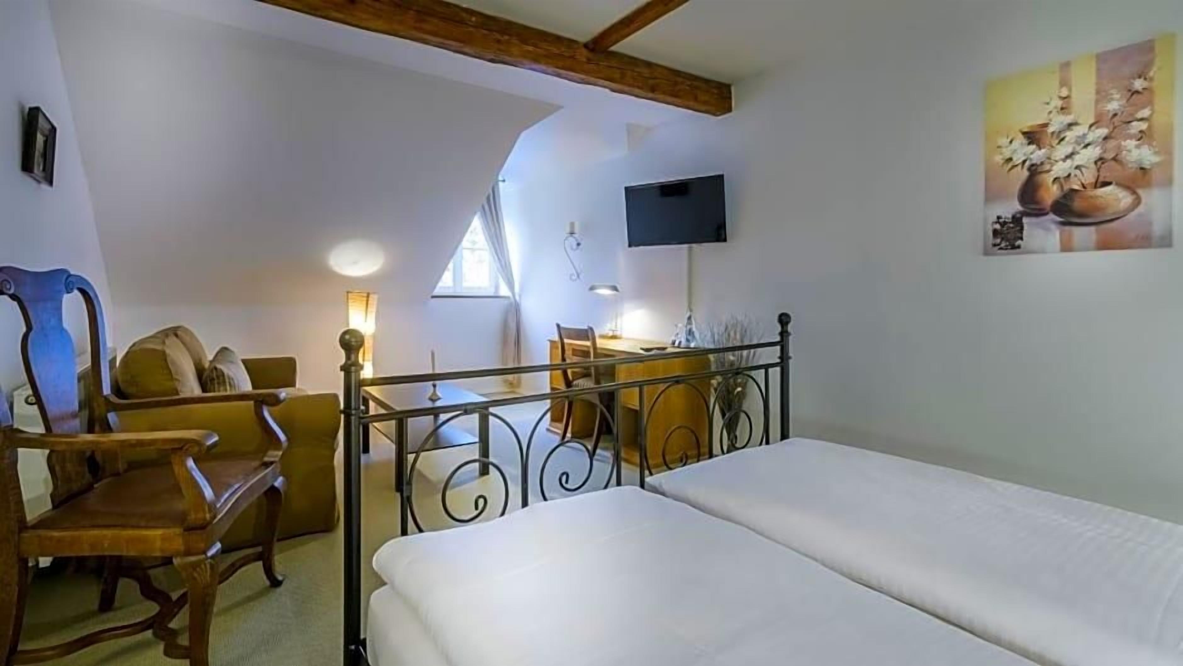 Une chambre à coucher avec un lit, un bureau, une chaise et un téléviseur fixé au mur.