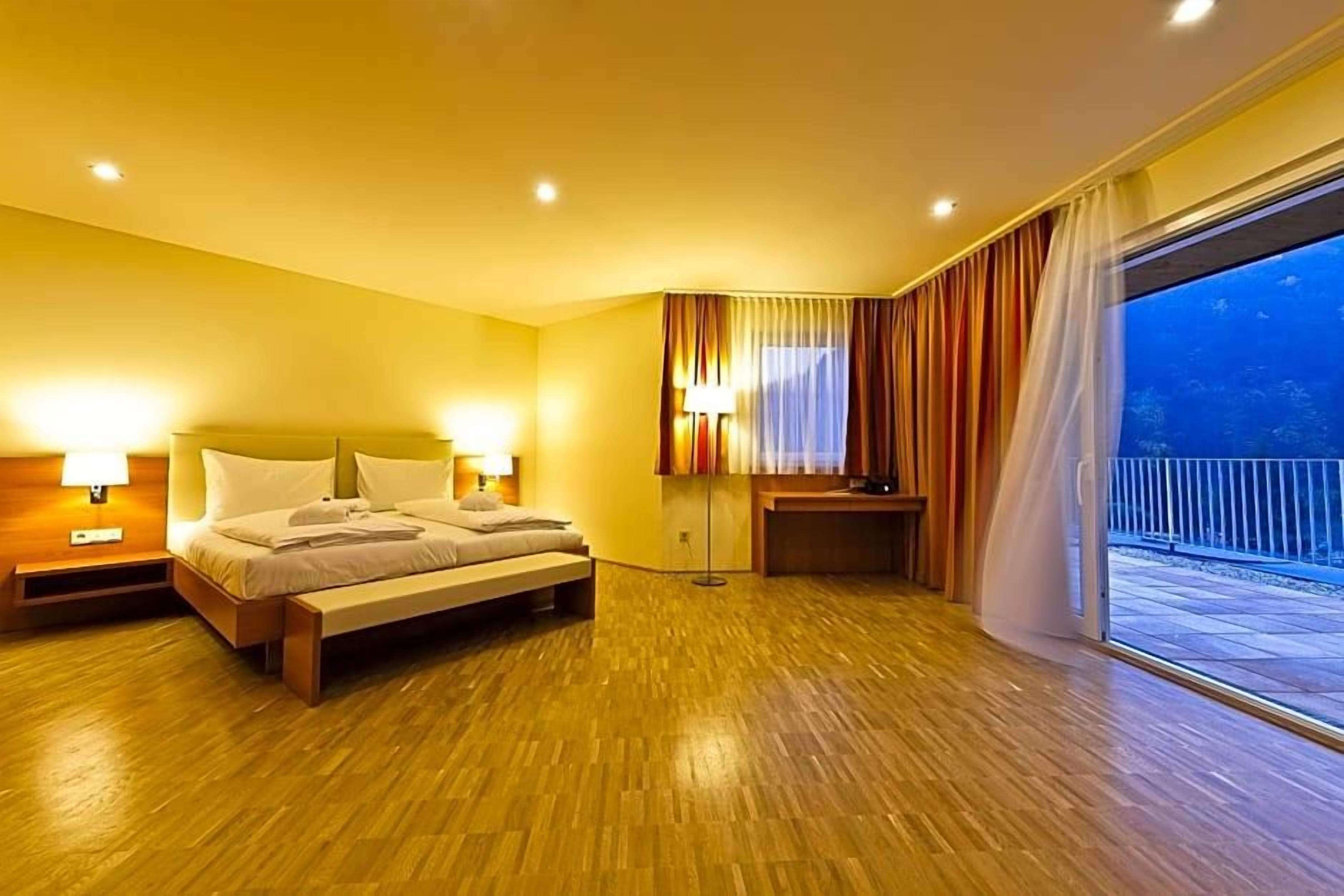 Habitació d'hotel amb un llit, làmpades de nit, escriptori i vista a l'exterior.