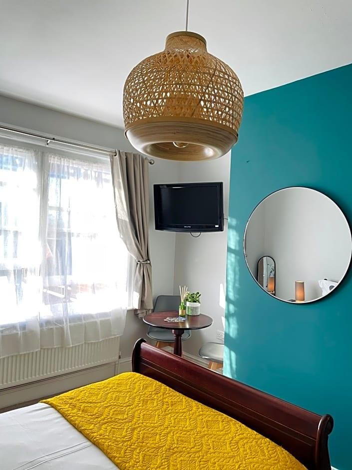 Une chambre d’hôtel avec un lit, un miroir rond, une télévision et une fenêtre avec des rideaux.
