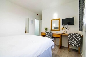 A hotel room with a bed, a desk, a chair, a television, and a mirror. - The Residence Jaipur (York)