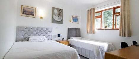 Habitación de hotel con dos camas, un escritorio de madera y una ventana con cortinas.