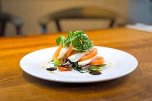 Un plato blanco con una ensalada sobre una mesa de madera.