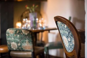 Un comedor con una mesa y sillas, un florero con flores y un fondo desenfocado.