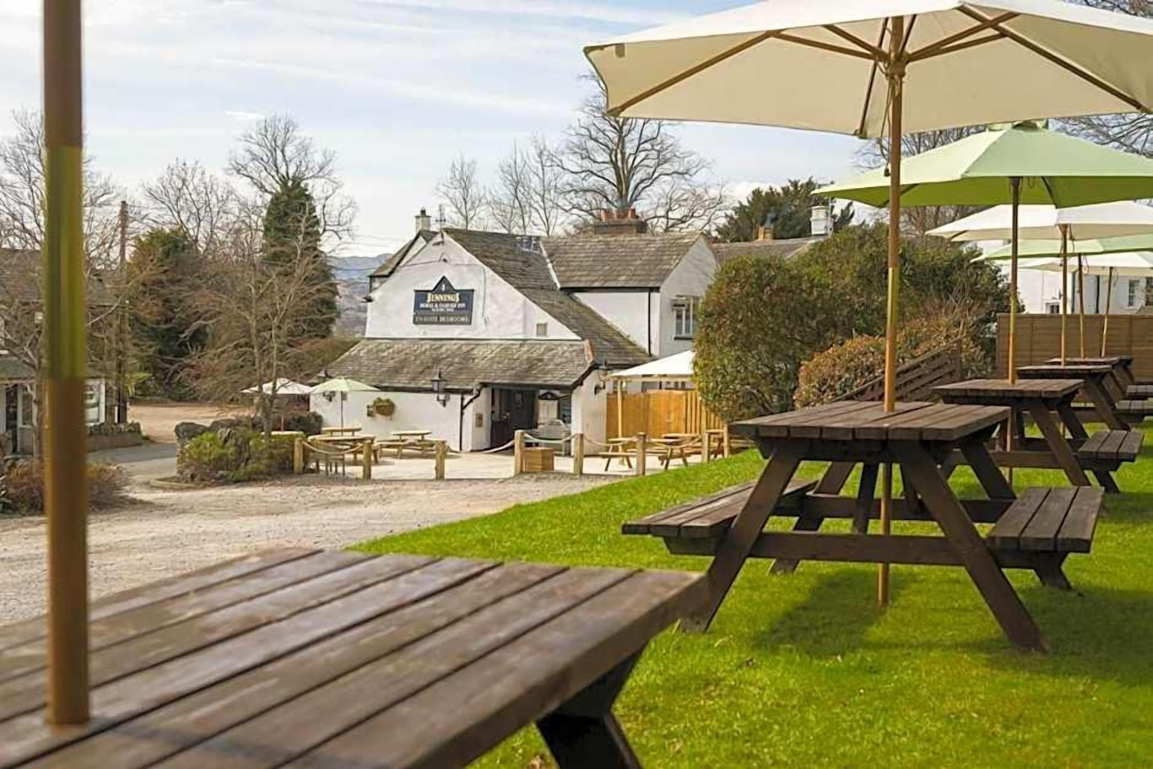A building with a sign that reads 'The Inn of the Black Dog.' There are picnic tables and umbrellas in the foreground.