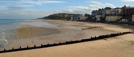 A beach with a sandy shore, a wooden barrier, and buildings in the background.