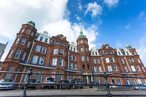 A large, historic building with multiple stories and distinctive architectural features, including a tower with a green dome. - De Paris (Cromer)