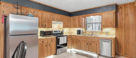 A modern kitchen with wooden cabinets, stainless steel appliances, and a marble countertop.